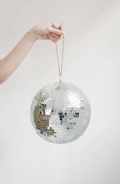 Hand holding disco ball on string  clipart