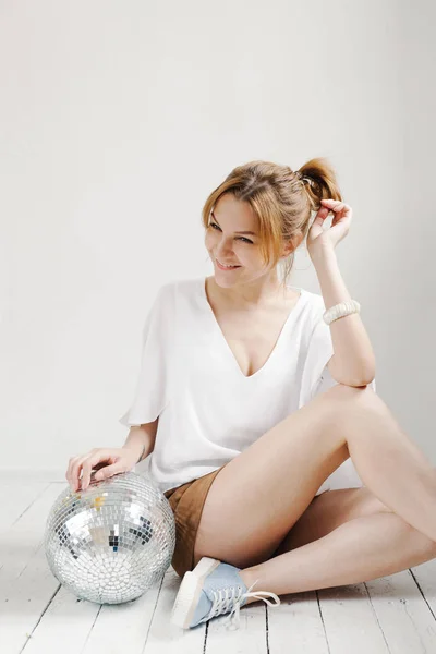 Hipster νεαρή γυναίκα κρατώντας την μπάλα disco και ποζάρουν χαρωπά σε λευκό φόντο — Φωτογραφία Αρχείου