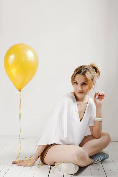 Porträtt av söt flicka i en studio leende och leker med gula ballonger, bakgrund med copyspace — Stockfoto