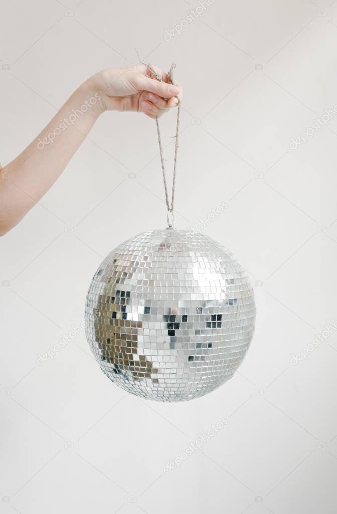 Hand holding disco ball on string 