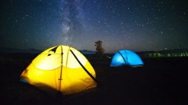 İki gezginler yaz saati meteor yağmurunda izliyor. Timelapse üzerinde kamp çadır gece gökyüzünde hareket yıldız.