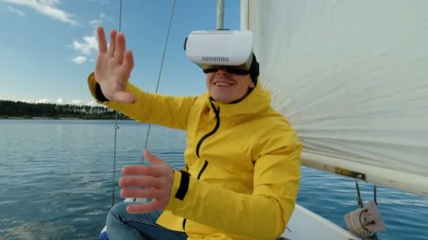 Mann mit Virtual-Reality-Brille, genießt es, auf einem Segelboot zu sitzen und glücklich auszusehen. — Stockvideo