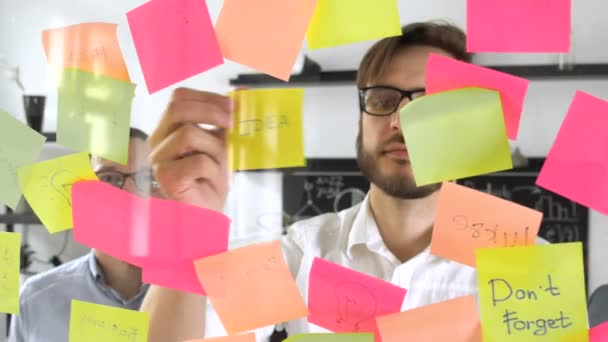 Man inlägg i fästis medan mötet i office på etiketten skrivs idé — Stockvideo
