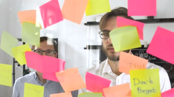 Чоловік розміщується в липкій ноті під час зустрічі в офісі на наклейці пишеться N1 номер один — стокове відео