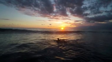 Genç kadın okyanus ağır çekimde sörf tahtası, kürek çekmeye