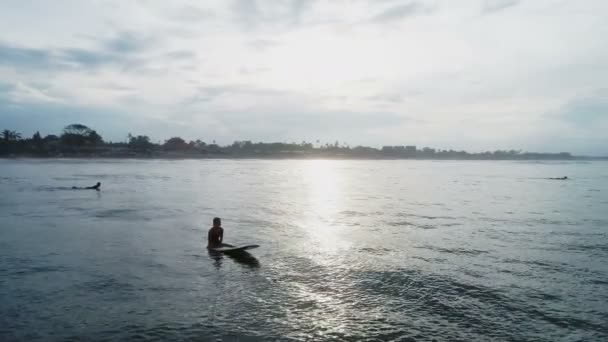 Вид с воздуха: девушка расслабляется сидя на доске для серфинга замедленной съемки — стоковое видео