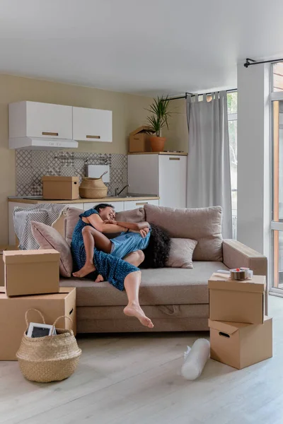 Mamma och dotter multirace flytta till en ny lägenhet. Ha kul hoppa och spela på soffan. — Stockfoto