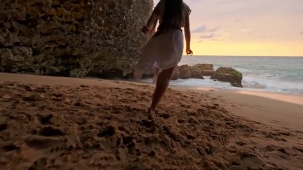 夕日や日の出水に沿って実行しているドレスのブルネットの女性。ビーチのサンセットで踊る幸せな屈託のない女。幸せな自由なライフ スタイル コンセプト. — ストック動画