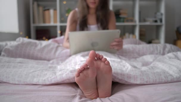 Teknologi, internet dan konsep masyarakat - wanita muda yang bahagia berbaring di tempat tidur dengan komputer tablet pc di kamar tidur rumah — Stok Video