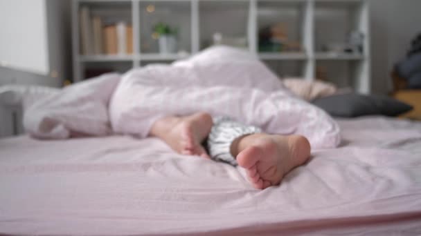 Vue rapprochée des pieds couchés sur un oreiller blanc doux au lit — Video