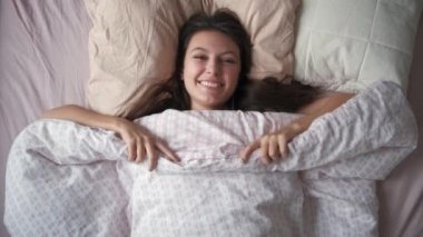 Genç ve çekici bir kadının sabahları yatakta uzanırken ellerini açması.