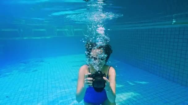 Una joven se sumerge en el agua. Vista desde debajo del agua, spray. concepto de vacaciones de verano, saltar a la piscina, Niña nadando bajo el agua con la cámara . — Vídeo de stock