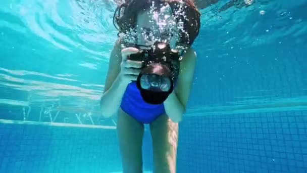 年轻女子潜入水中。 从水底看，喷水。 暑假的概念，跳到游泳池里，女孩带着相机在水下游泳. — 图库视频影像