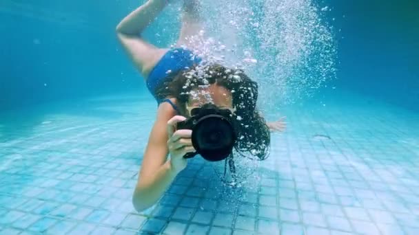 Chica viajera en Asia. Mujer joven feliz con hermoso pelo largo nadar bajo el agua con cámara en la piscina de aguas termales. Indonesia, Bali . — Vídeos de Stock