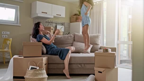 Молодая мать и ее маленькая дочь прыгают на кровати. Забавный бой подушками. Играйте вместе и наслаждайтесь моментом Семейное время на выходных . — стоковое видео