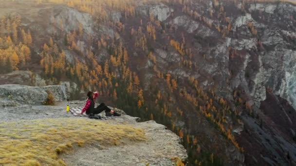 Mujer disfrutar de la puesta de sol sentado en la cima de una alta montaña — Vídeo de stock