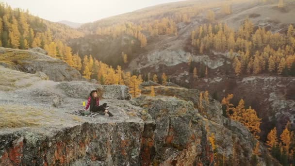 Mujer disfrutar de la puesta de sol sentado en la cima de una alta montaña — Vídeos de Stock