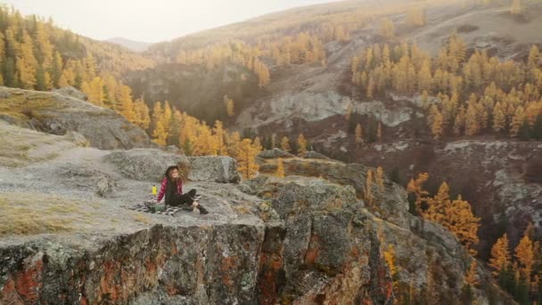 Kvinna njuta av solnedgången sitter på toppen av ett högt berg — Stockvideo