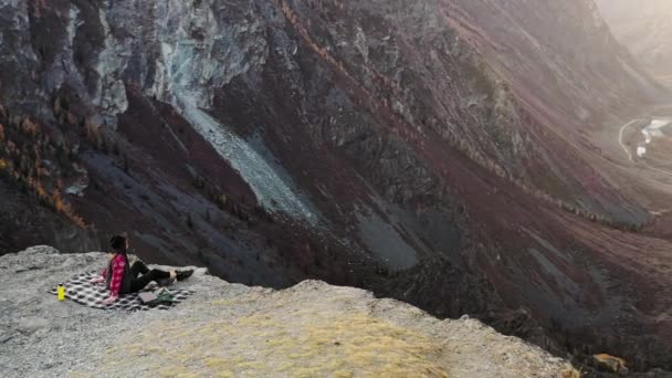 Mujer disfrutar de la puesta de sol sentado en la cima de una alta montaña — Vídeos de Stock