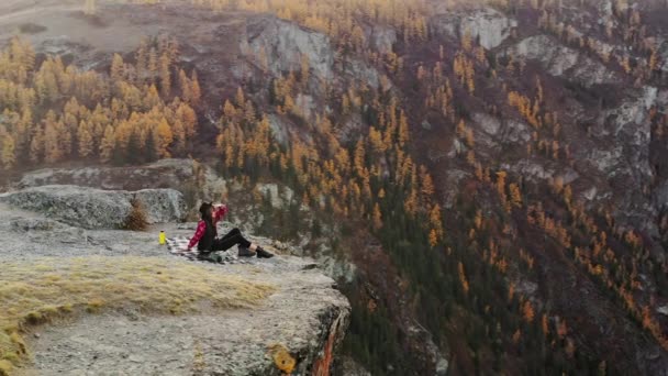 Mulher desfrutar do pôr do sol sentado no topo de uma montanha alta — Vídeo de Stock