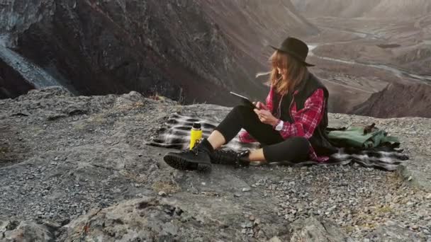 Mujer excursionista uso tableta digital en el acantilado pico de montaña — Vídeos de Stock