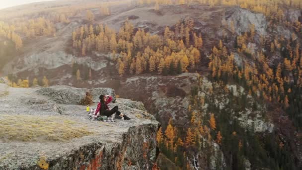 Mujer disfrutar de la puesta de sol sentado en la cima de una alta montaña — Vídeos de Stock