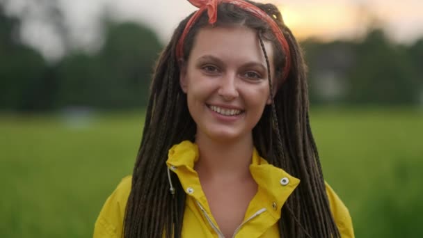 Close up retrato da jovem mulher sorrindo no vento olhando para o pôr do sol sobre a floresta — Vídeo de Stock