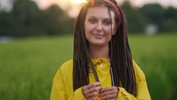 Close up retrato da jovem mulher sorrindo no vento olhando para o pôr do sol sobre a floresta — Vídeo de Stock