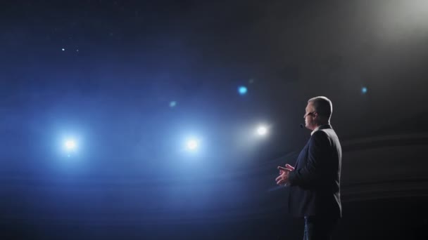 Showman. Moyen Âge Homme artiste, présentateur ou acteur sur scène. Bras sur les côtés, fumée sur fond de projecteur. Portrait arrière d'un orateur masculin parlant au microphone, pointant du doigt — Video