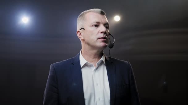 Showman. Moyen Âge Homme artiste, présentateur ou acteur sur scène. Bras sur les côtés, fumée sur fond de projecteur. Portrait de face d'un orateur masculin parlant au microphone, pointant du doigt 