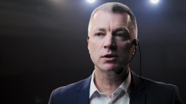 Showman. Moyen Âge Homme artiste, présentateur ou acteur sur scène. Bras sur les côtés, fumée sur fond de projecteur. Portrait de face d'un orateur masculin parlant au microphone, pointant du doigt 