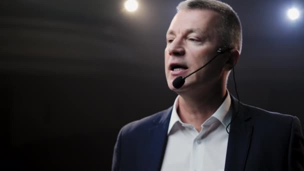 Showman. Moyen Âge Homme artiste, présentateur ou acteur sur scène. Bras sur les côtés, fumée sur fond de projecteur. Portrait de face d'un orateur masculin parlant au microphone, pointant du doigt 