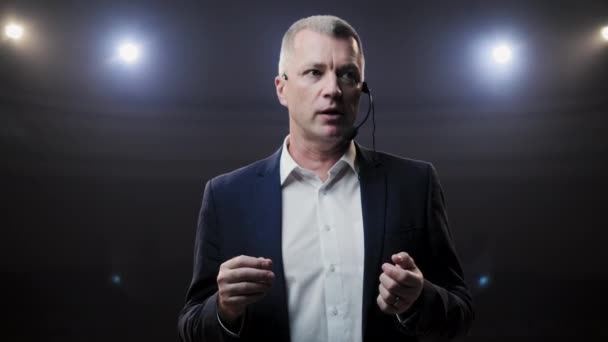 Portrait d'hommes parlant à travers un micro dans une salle de conférence sombre. L'homme parle dans les microphones lors de la conférence de presse. Profil d'un homme politique mature parlant passionnément de tribune 
