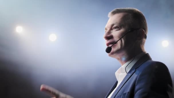 Showman. Moyen Âge Homme artiste, présentateur ou acteur sur scène. Bras sur les côtés, fumée sur fond de projecteur. Portrait de face d'un orateur masculin parlant au microphone, pointant du doigt 