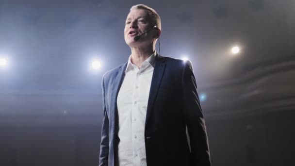 Portrait of men speaking through a microphone in dark conference hall. Person says about marketing and management for successful sales to college students indoors closeup. Professional ideas, politics — Stock Video