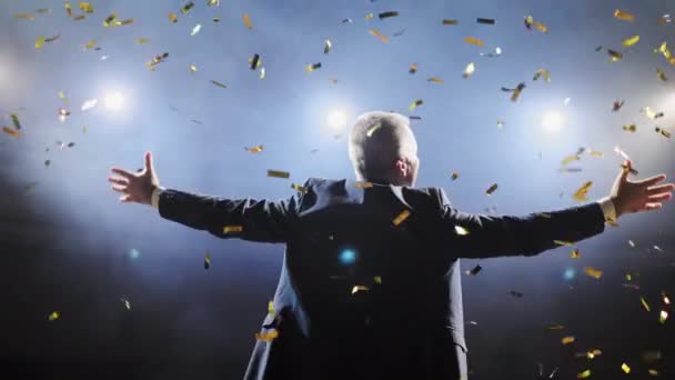 Un exitoso hombre de negocios con las armas levantadas celebrando su victoria. Celebrando el éxito. Vista de bajo ángulo del joven empresario entusiasmado manteniendo los brazos levantados y expresando positividad mientras está parado en el escenario . — Vídeos de Stock