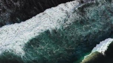 Büyük dalgalar yukarıdan geliyor. Mavi turkuaz okyanusta 4K drone görüntüsü, dalga kırma, badana. Deniz üzerinde güneşli bir gün. Büyük dalgalar sahil şeridini vurdu. Güçlü dalgalar Bali, Endonezya