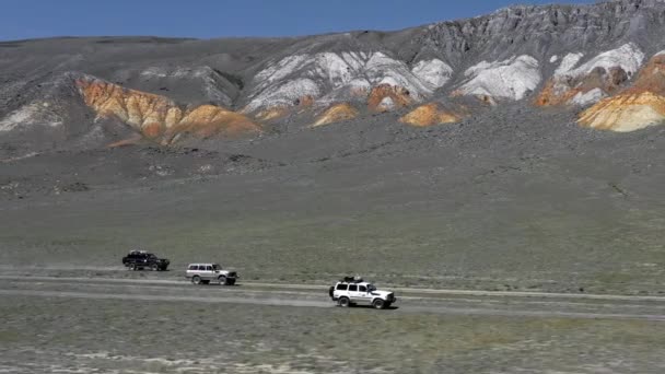 Pohled na safari vozidlo jedoucí po pískové cestě. Letecký off road 4x4 auto jízda podél štěrkové stezky cesty v blízkosti suché pouštní hory.Pamir Highway hedvábí road trip dobrodružství — Stock video