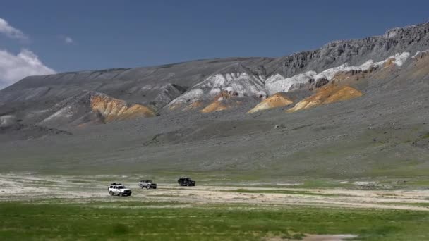 View of safari vehicle driving on sand tracks road. Aerial over off road 4x4 car driving along gravel trail path near arid desert mountains.Pamir Highway silk road trip adventure — Stock Video