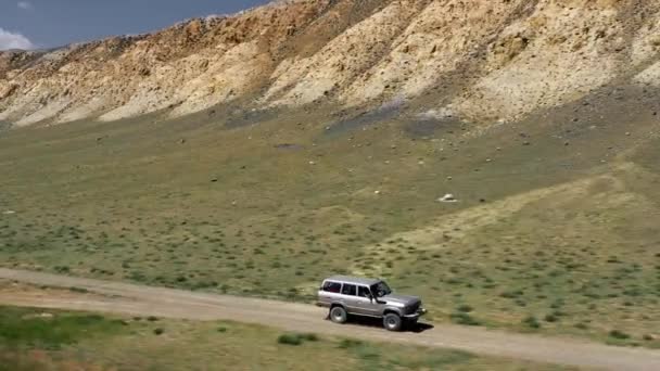 Widok pojazdu safari jazdy po drogach piasku. Aerial over off road 4x4 car driving along a gravel trail path near suche pustynne góry.Pamir Jedwabna wycieczka autostrady przygoda — Wideo stockowe