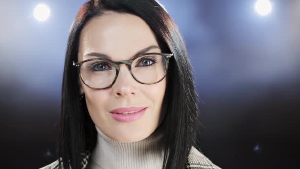 Középkorú nő szemüveggel közeli portré sötét háttérrel. Alkalmi üzletasszony néz boldog és mosolygós — Stock videók