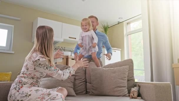 Active Family Group Move in Rent Real Estate. Positive Looking at Relocating or Unpacking of Carton Pack by Playful Family. Little girl jumps on hands to mom. Enjoying Life or Dream — Stockvideo