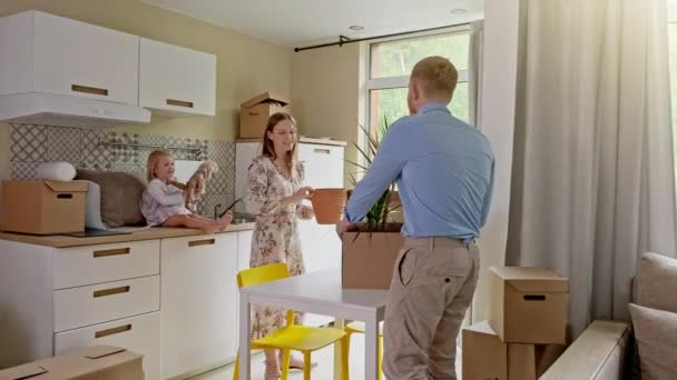 Junge Familie zieht in ein neues Zuhause. Nahaufnahme einer glücklichen jungen kaukasischen Familie, die in das neue, moderne, helle Haus mit großem Pappkarton zieht. Positiver Blick auf das Um- oder Auspacken von Kartonverpackungen. — Stockvideo