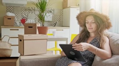 Arkasında kutular olan tablet kullanan bir kadın. Yeni evinde cep telefonu olan güzel bir kadının portresi.