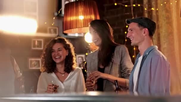 Mladí lidé něco slaví v kavárně. Cinkají sklenicemi s pivem a koktejly, popíjejí a klábosí. Moderní oslava v konceptu baru. — Stock video