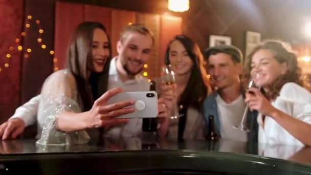 Joven alegre amigas tomando selfie en pub usando el teléfono. Amigos, hombres, mujeres, ocio, amistad y concepto de tecnología: amigos con teléfonos inteligentes que beben cerveza en el bar o pub — Vídeo de stock