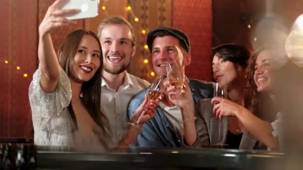 Joven alegre amigas tomando selfie en pub usando el teléfono. Amigos, hombres, mujeres, ocio, amistad y concepto de tecnología: amigos con teléfonos inteligentes que beben cerveza en el bar o pub — Vídeo de stock