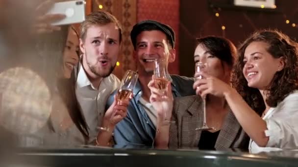 Joven alegre amigas tomando selfie en pub usando el teléfono. Amigos, hombres, mujeres, ocio, amistad y concepto de tecnología: amigos con teléfonos inteligentes que beben cerveza en el bar o pub — Vídeo de stock