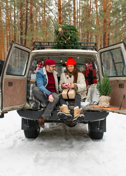 Caucasian couple tying fresh cut Christmas tree to a roof of a vintage SUV. Lifestyle, celebration, relationship — Stock Photo, Image