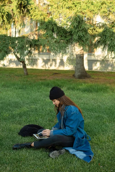 Krásná mladá studentka studuje pomocí tabletu v parku. Rekreační a studijní koncept — Stock fotografie